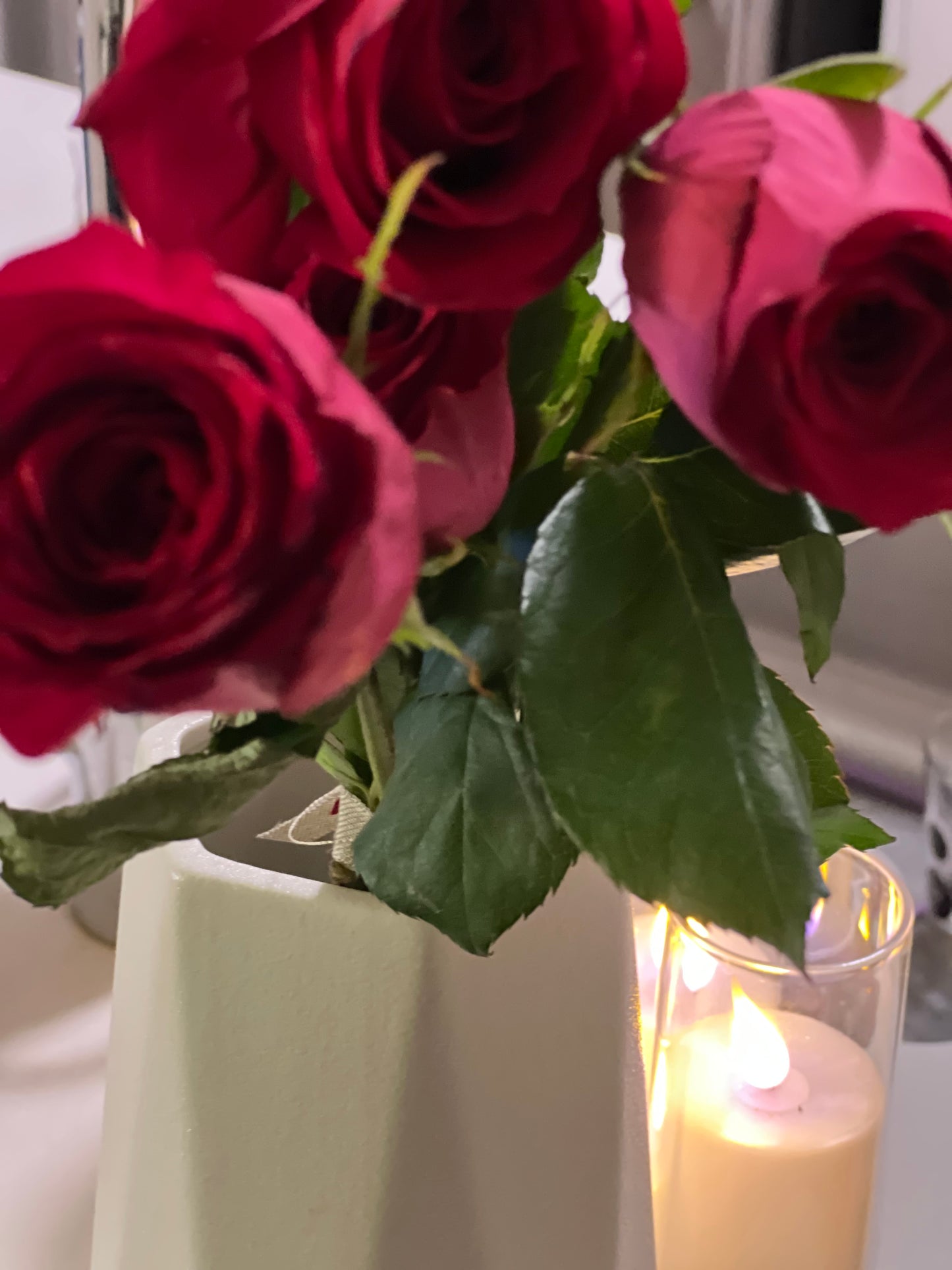 Three roses in a wine vase with a candle
