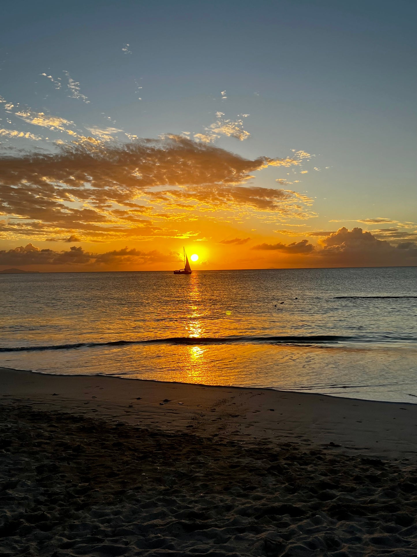 Beach sunset with boat in the ocean, with sun in the background