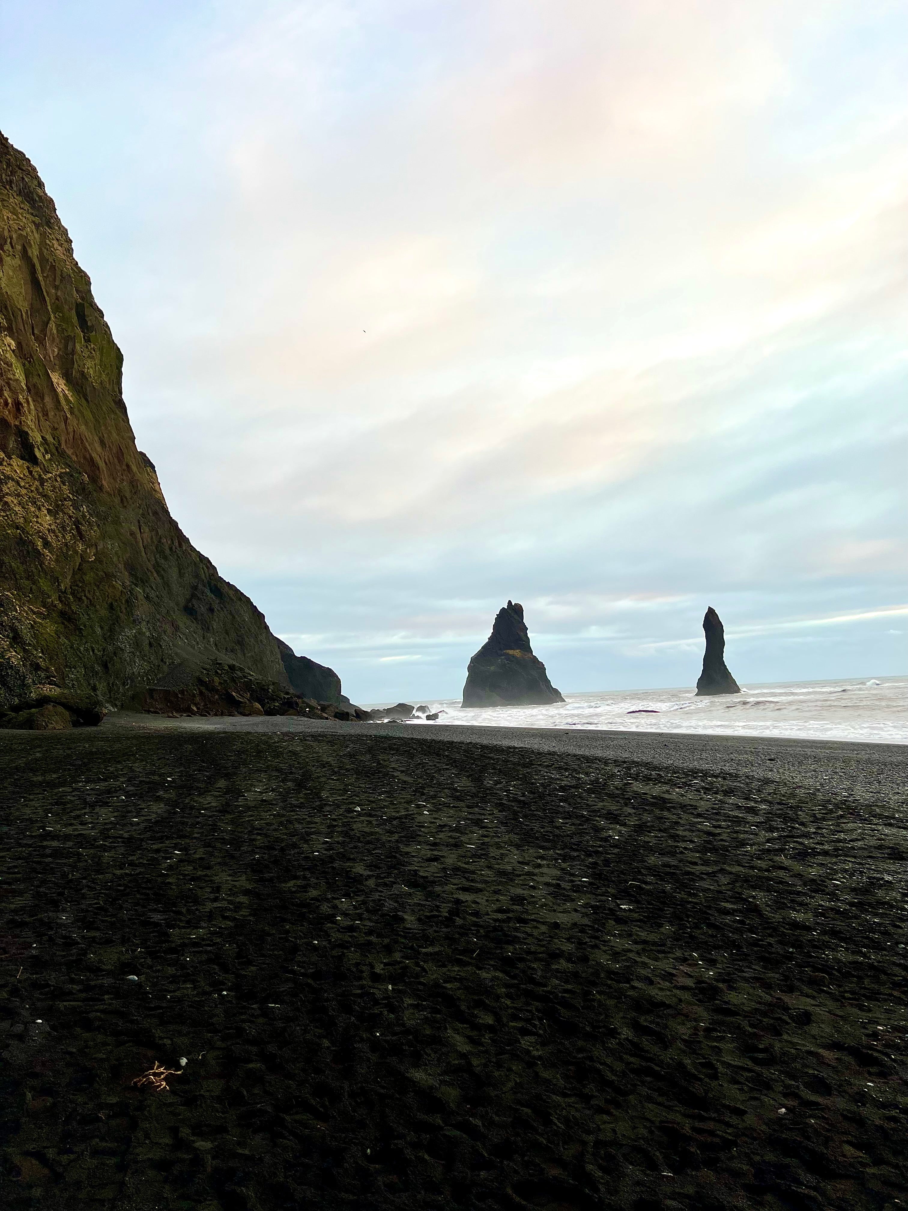 Black sand beach with ricks emerging from water in Iceland