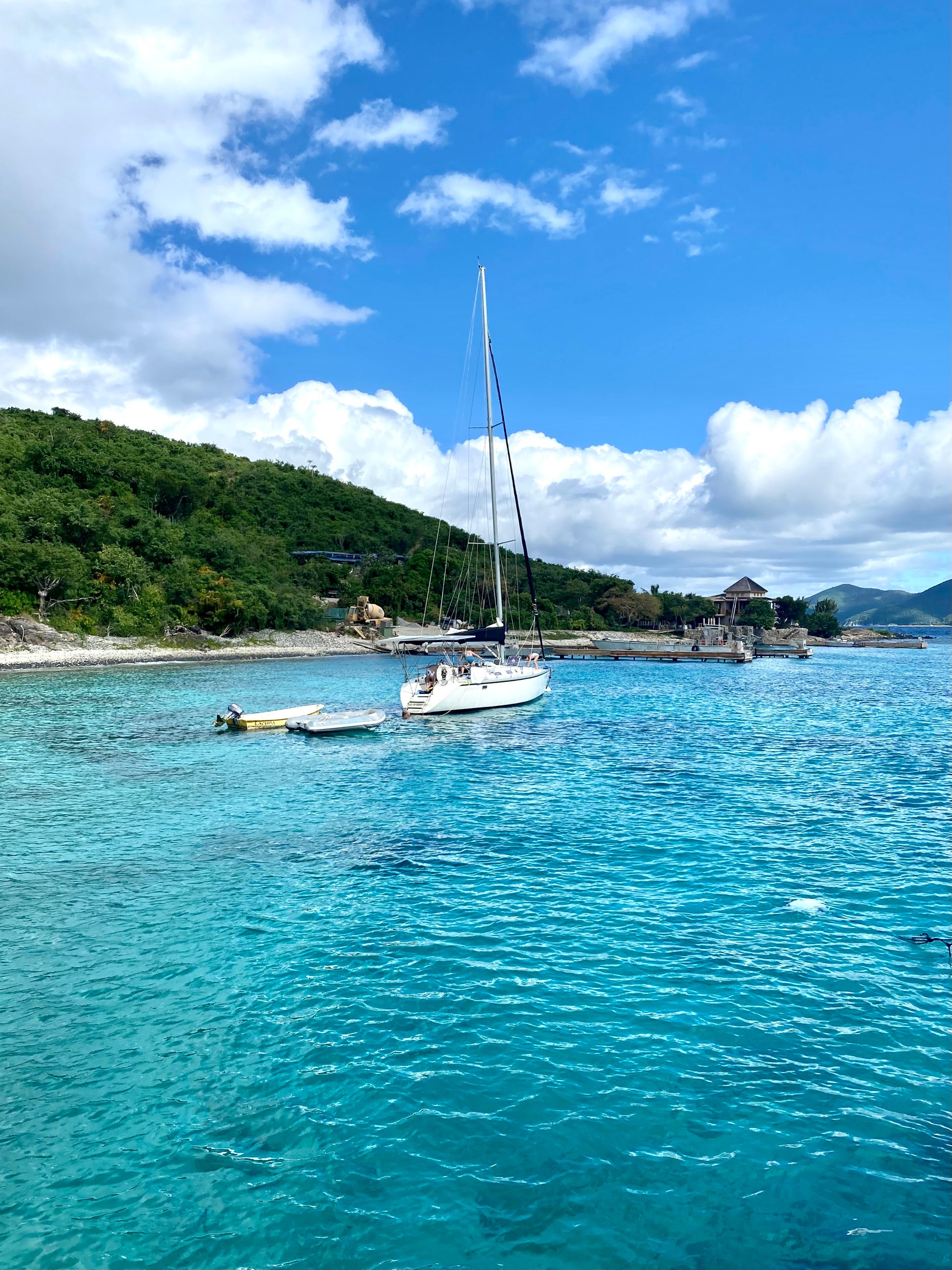 Boat in the ocean, surrounded by blue water with lush forest on the left