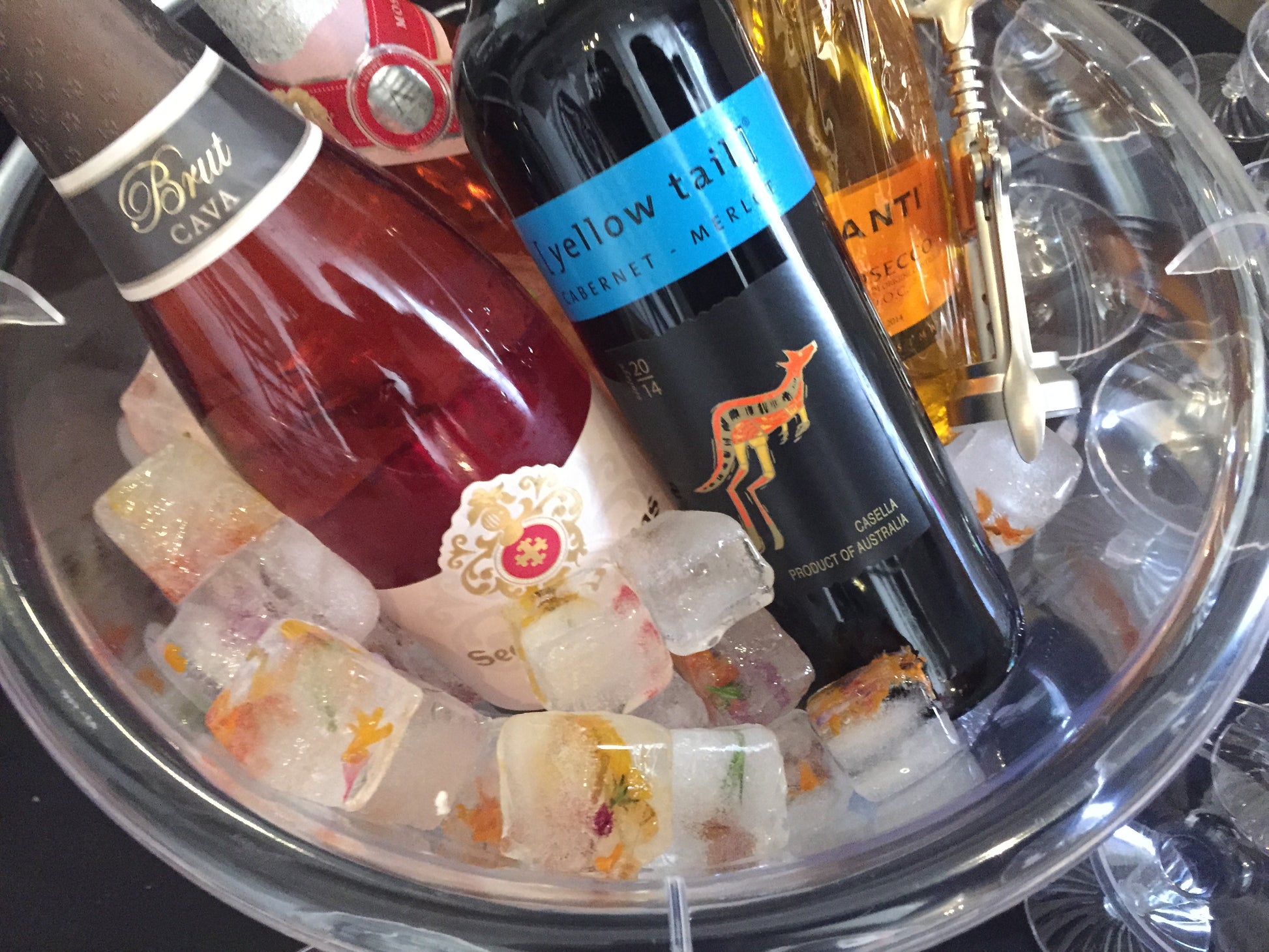 Bottles of wine in wine chiller container with ice filled with edible flowers