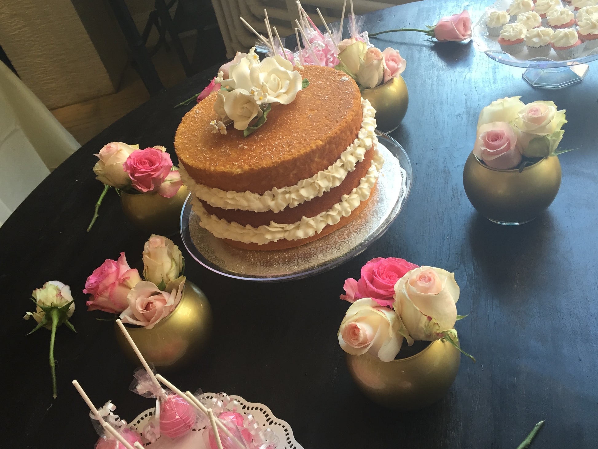 three tiered cake on a table surrounded by flowers in small vases